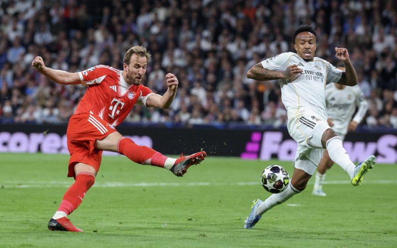 Bayern Munich's English forward #09 Harry Kane (L) shoots challenged by Real Madrid's Brazilian defender #03 Eder Militao during the UEFA Champions League quarter final first leg football match between Real Madrid CF and FC Bayern Munich at Santiago Bernabeu Stadium in Madrid on April 7, 2026. (Photo by Pierre-Philippe MARCOU / AFP)